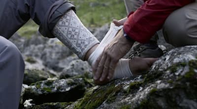 a person with a cast on their arm sitting on a rock