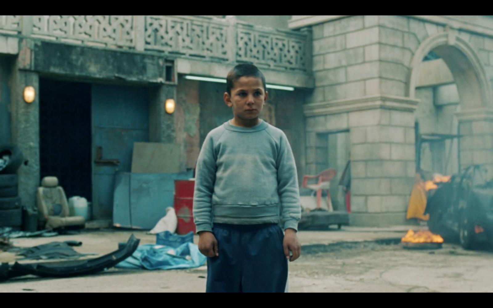 a young boy standing in front of a fire