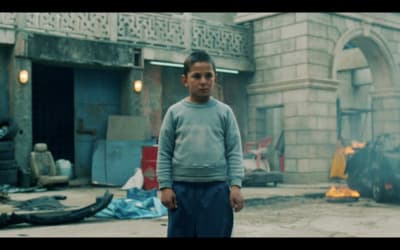 a young boy standing in front of a fire
