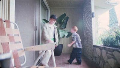 a man standing next to a little boy on a porch