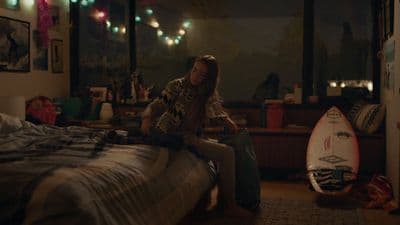 a person sitting on a bed with a surfboard