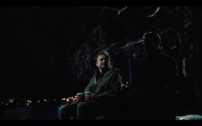 a man sitting next to a man holding a cup of coffee