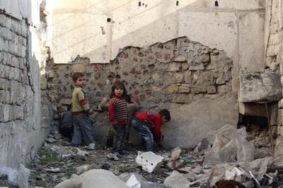 a group of young boys standing next to a pile of rubble