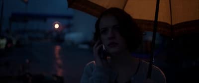 a woman talking on a cell phone under an umbrella