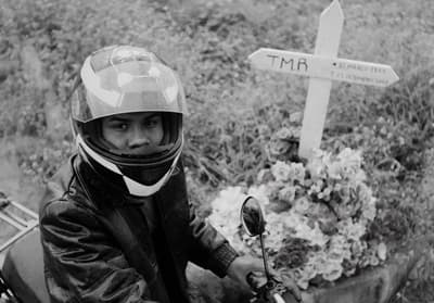 a man riding a motorcycle next to a cross