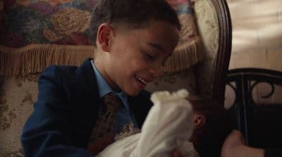 a young boy holding a baby in a chair