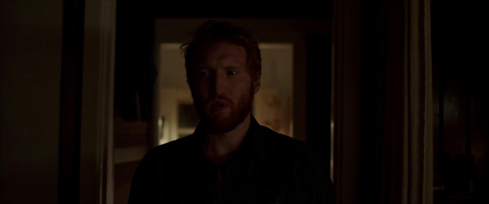 a man with a beard standing in a dark room