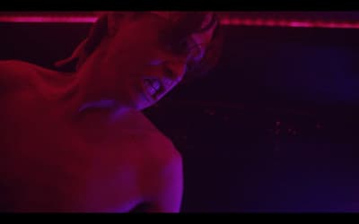 a shirtless man with his mouth open in a dark room