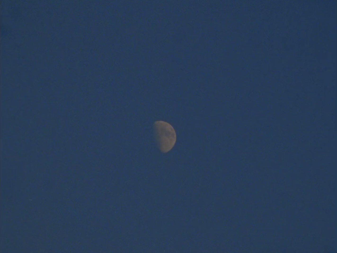 a half moon in a clear blue sky