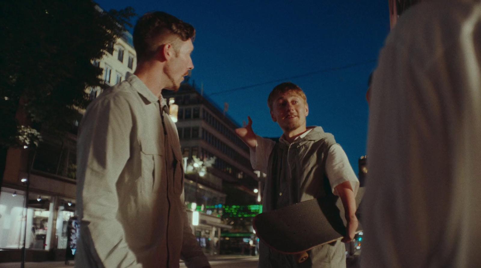 two men standing on the side of a road talking