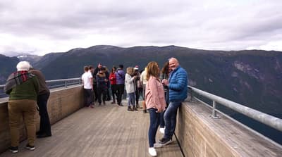 a group of people standing on a bridge overlooking a mountain