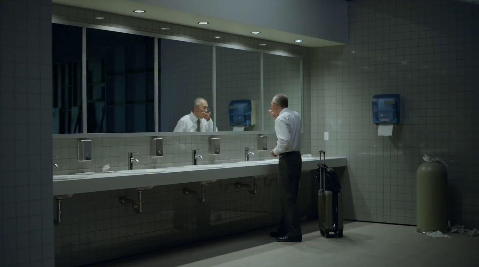 a couple of men standing in front of a bathroom mirror