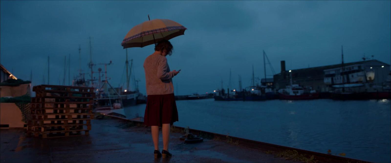 a woman standing on a dock holding an umbrella