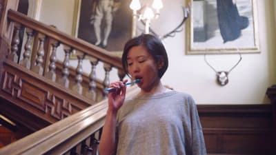 a woman brushing her teeth in front of a staircase