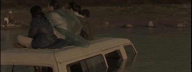 a group of people sitting on top of a van in the water