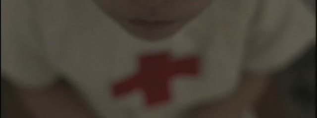 a blurry photo of a young boy with a red cross on his shirt
