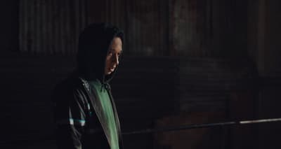 a man in a hoodie standing in a dark room