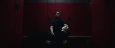 a man sitting on a bench in a locker room