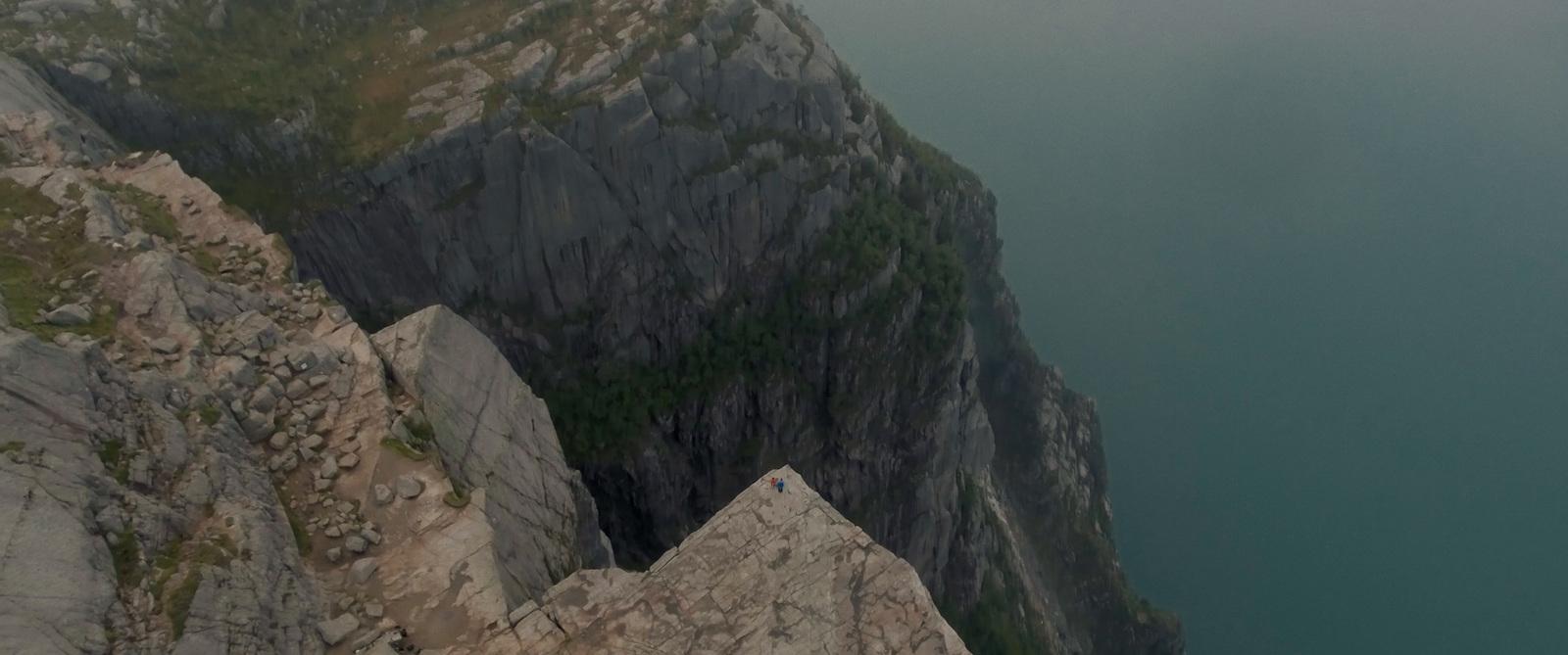 a man is standing on top of a cliff overlooking a body of water