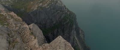 a man is standing on top of a cliff overlooking a body of water