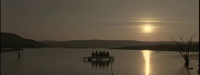 a group of people sitting on a boat in the middle of a lake