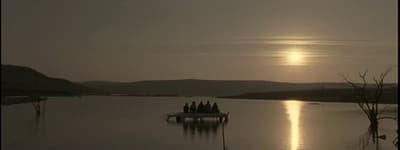 a group of people sitting on a boat in the middle of a lake