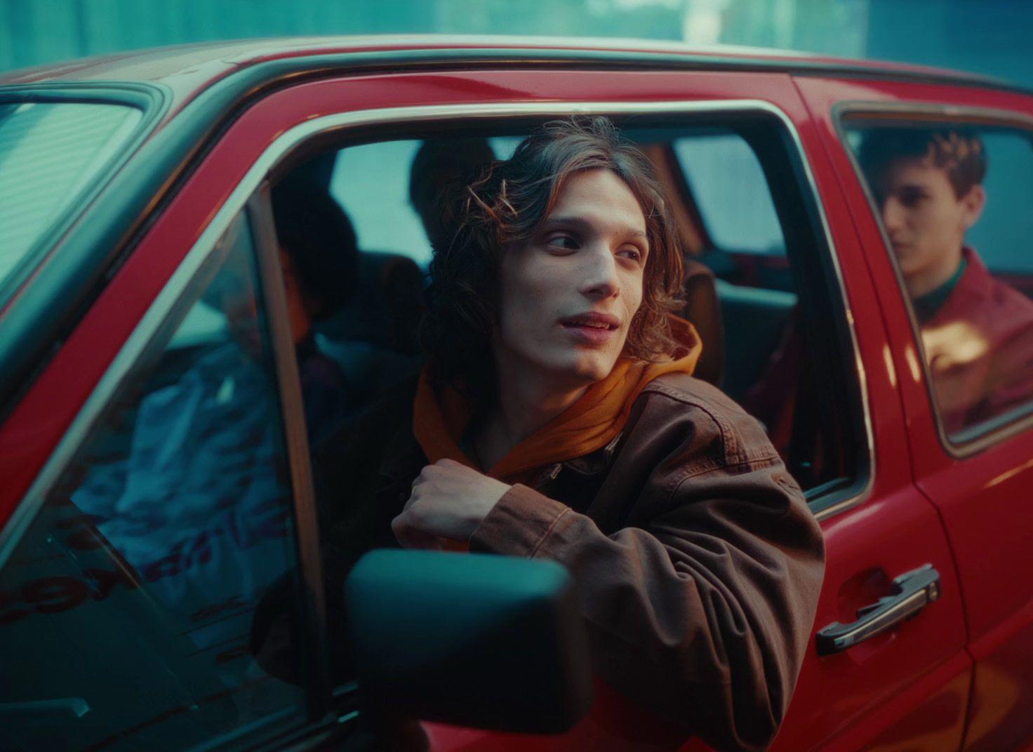 a woman sitting in a red car next to a man