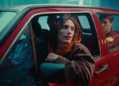 a woman sitting in a red car next to a man