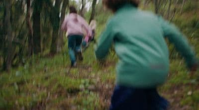a blurry photo of two people running through a forest