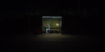a man sitting on a bench in the dark