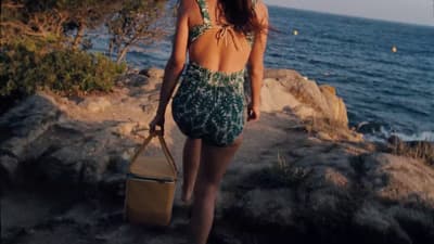 a woman in a bathing suit walking along the beach