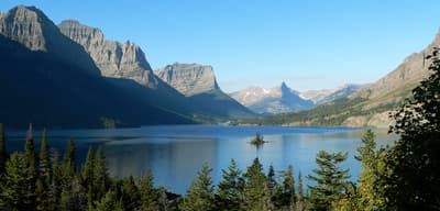 a lake surrounded by mountains with a boat in the middle