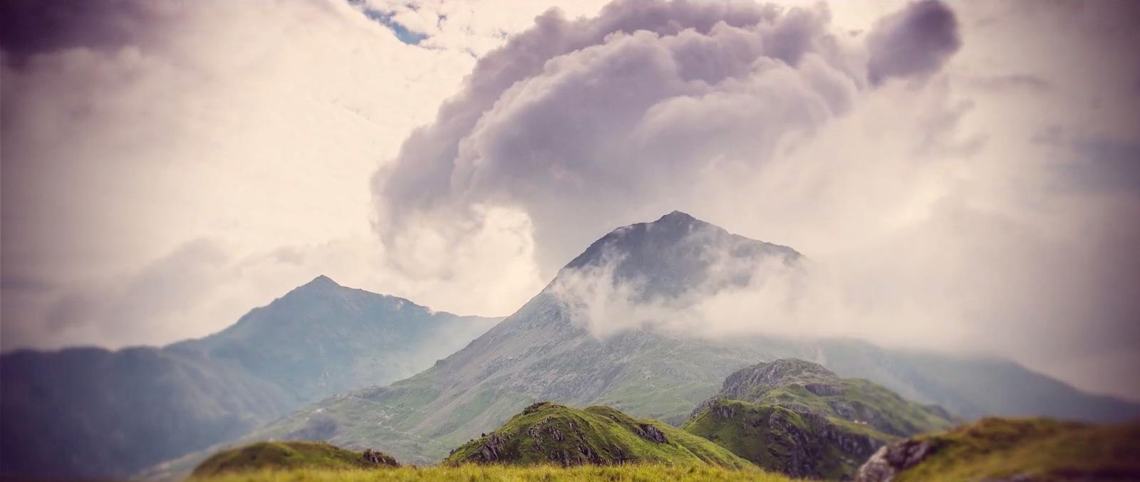 a very tall mountain with some clouds in the sky