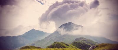 a very tall mountain with some clouds in the sky
