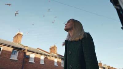 a woman looking up at a flock of birds in the sky