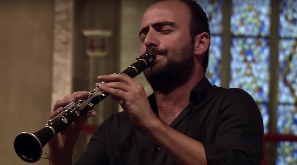 a man playing a flute in front of a stained glass window