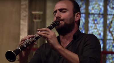 a man playing a flute in front of a stained glass window