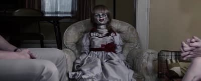 a creepy doll sitting in a chair in a living room