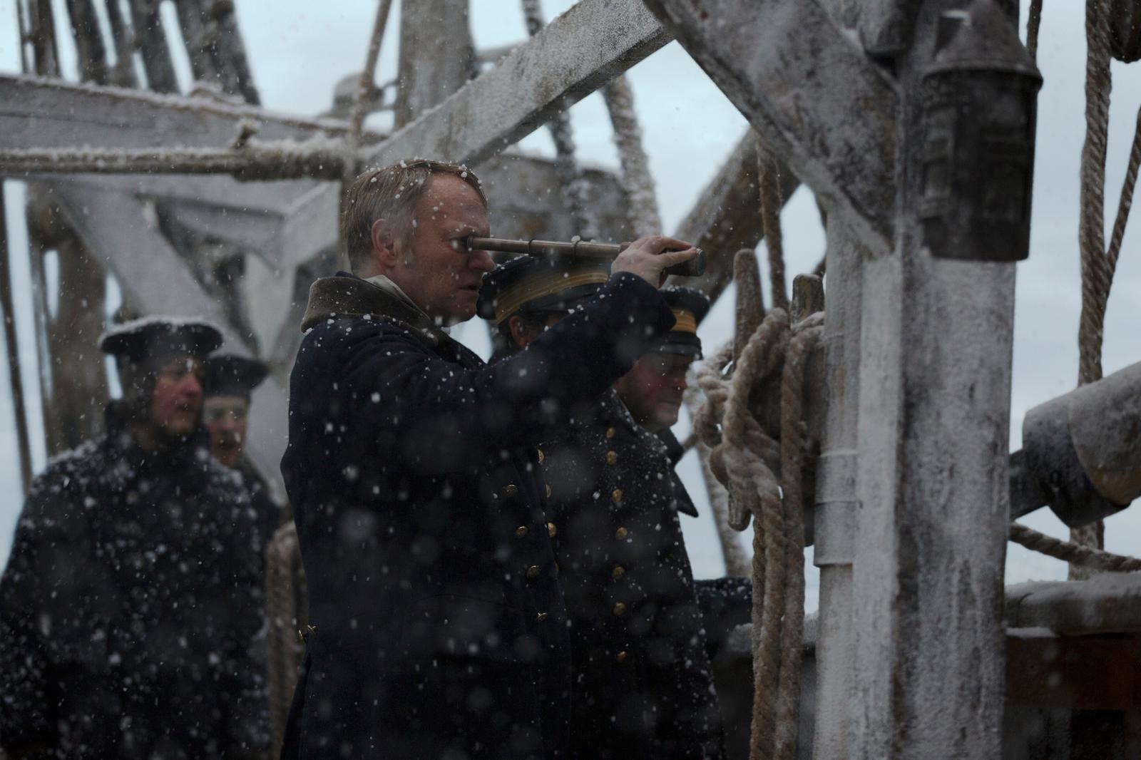 a group of men standing on top of a boat in the snow