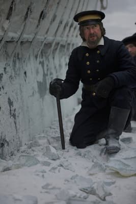 a man kneeling down in the snow with a cane