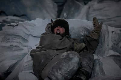 a man laying on top of a pile of ice