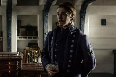 a man in a coat standing in a room