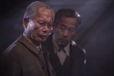 two men standing next to each other in a dark room
