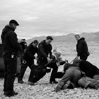 a group of men standing around a man laying on the ground