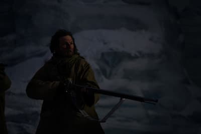 a man holding a gun in a dark cave