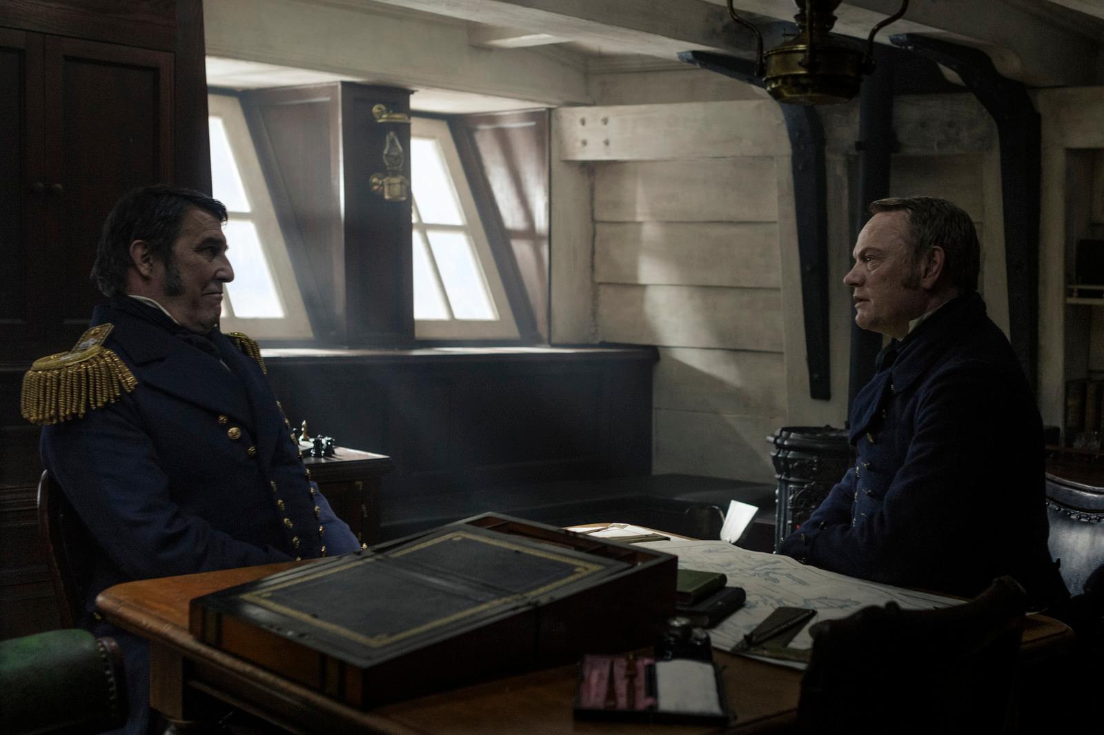 two men sitting at a table in a room