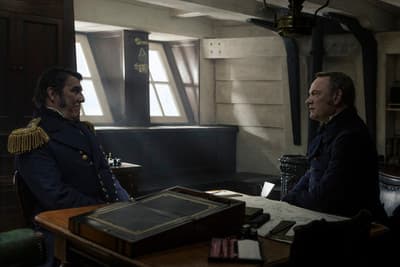 two men sitting at a table in a room
