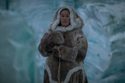 a woman in a fur coat standing in front of a glacier