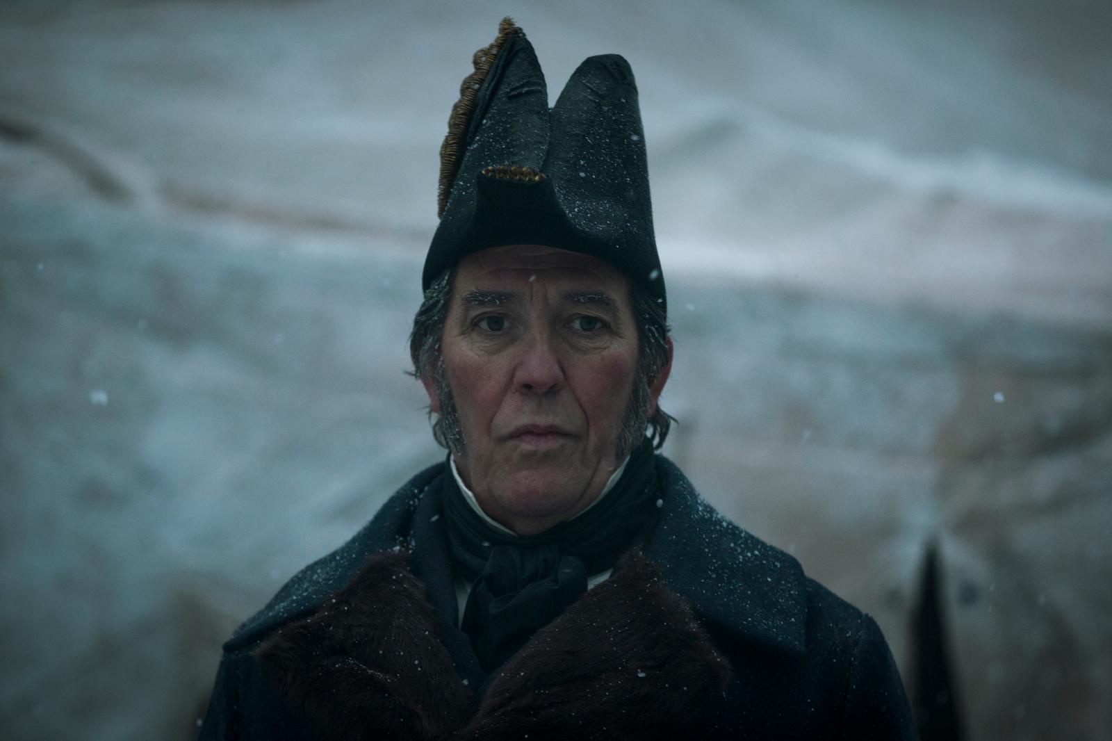 a man wearing a hat and coat in the snow