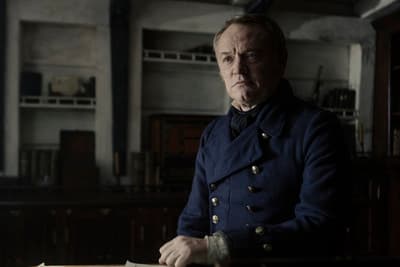 a man in a blue coat sitting at a table